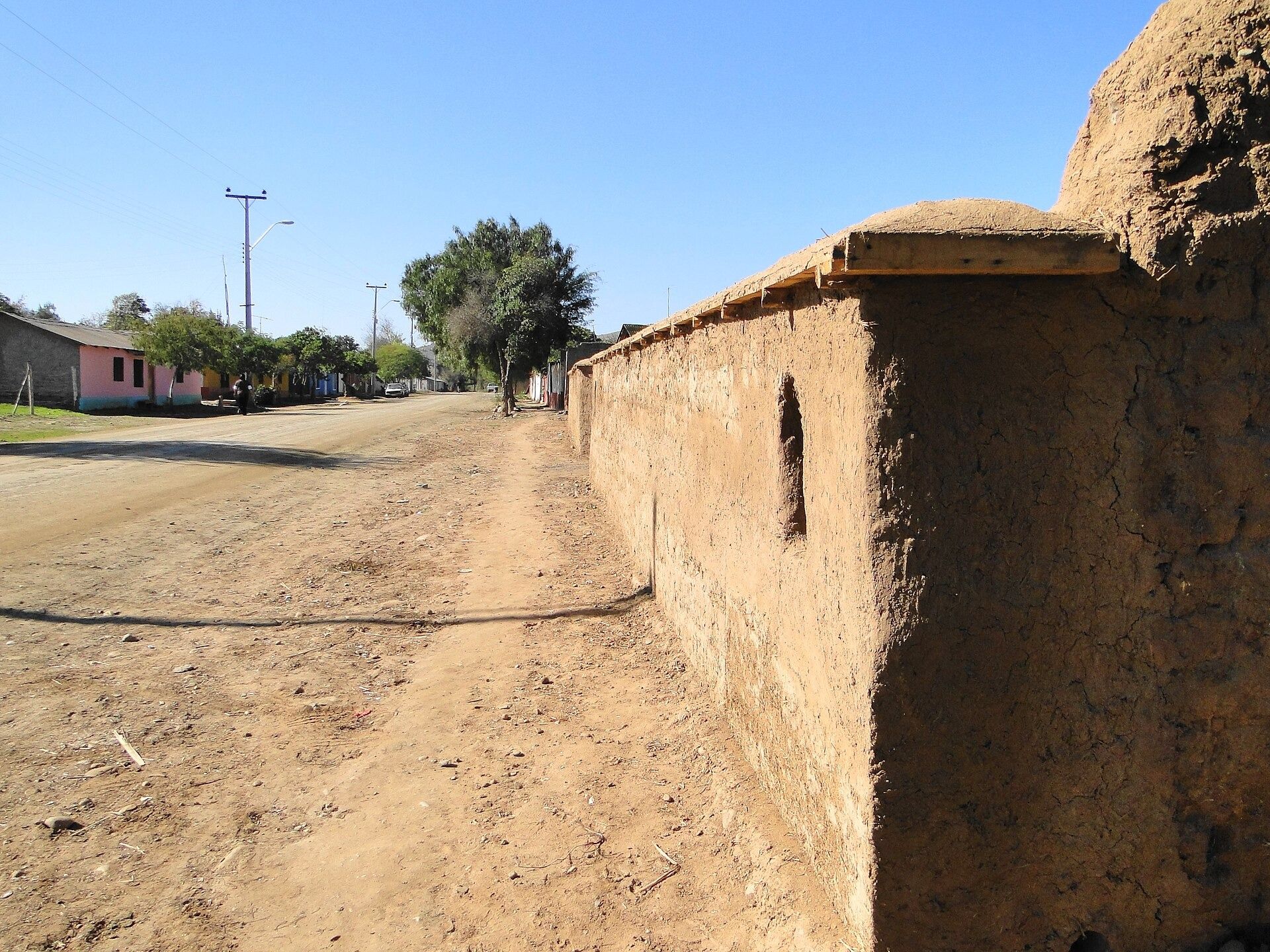 Muro de tierra cruda junto a una calle de tierra en Barraza